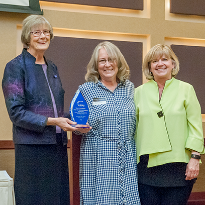 Sue Maes, dean of K-State Global Campus, presents the 2016 UPCEA Central Region Engagement Award to Kerri Ebert and Debbie Hagenmaier, Women Managing the Farm committee members, at the K-State Global Campus Honors and Awards Reception in May 2017.